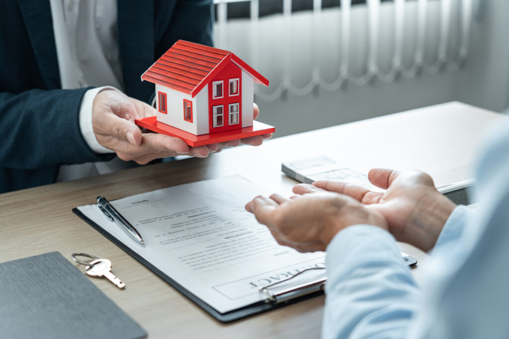 real estate broker agent holding house model and sending to the